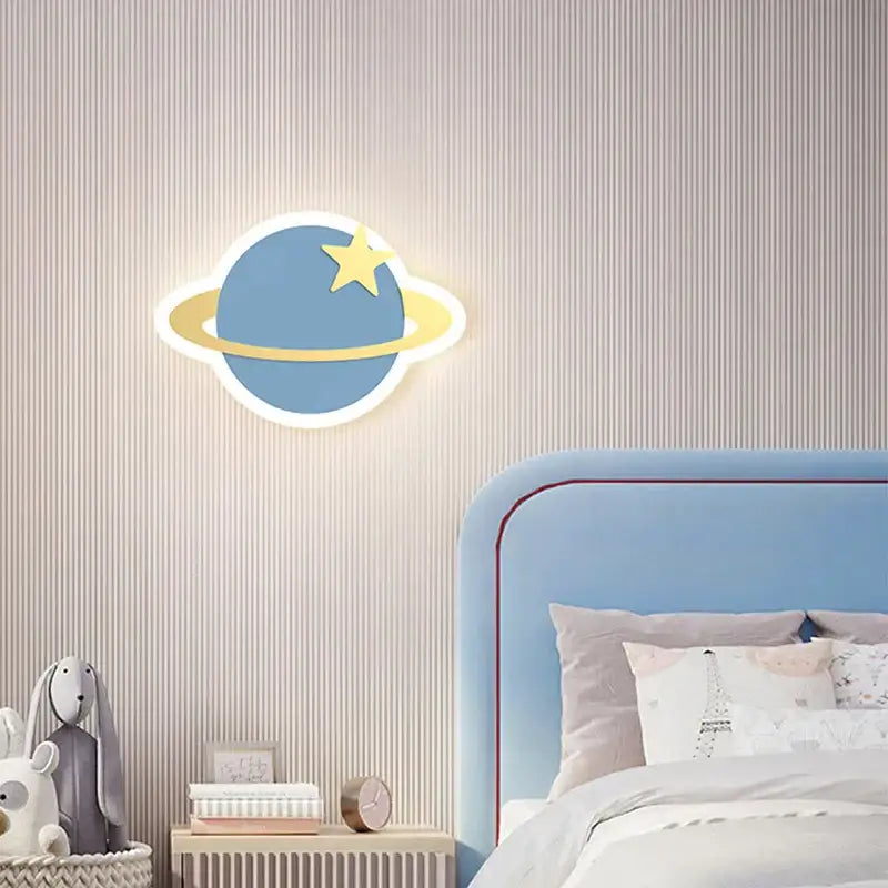 Blue planet-shaped decorbites night light with yellow ring and star illuminated against striped wallpaper for room crown clouds rocket