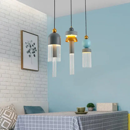 Three modern matte gray and gold-accented glass pendant lights with clear fringe for bedrooms and dining tables
