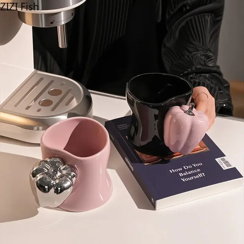 A glossy black ceramic decorbites chili handle cup with pink pumpkin handle and matching pink mug with silver flower accent