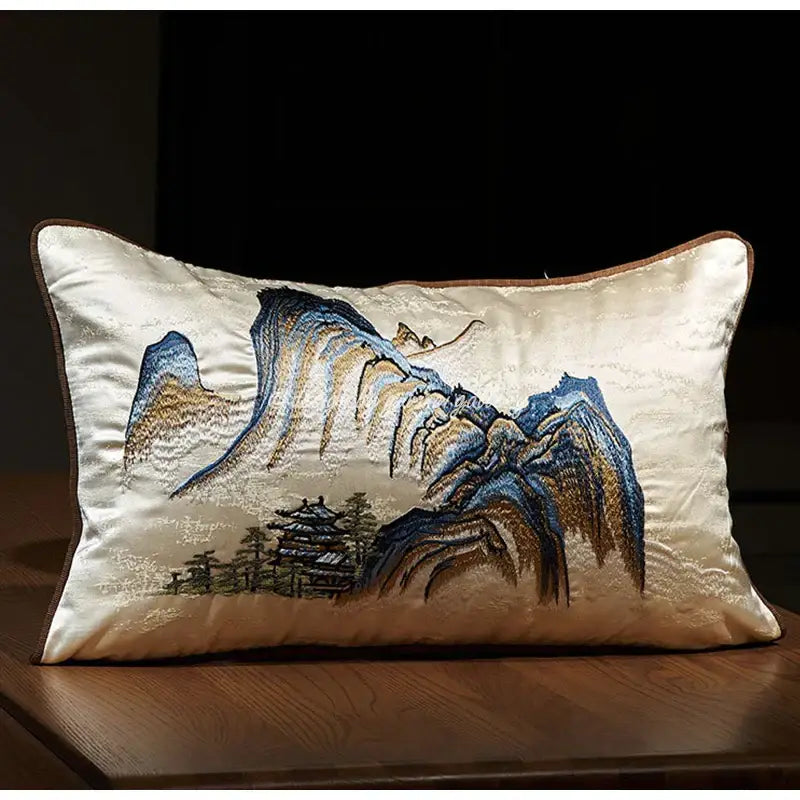 Cream-colored satin pillow cover with chinoiserie landscape embroidered in blue and gold featuring a pagoda design