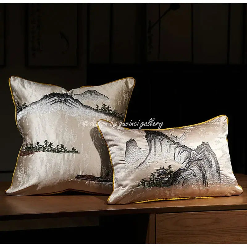 Cream-colored satin pillow cover with intricate black and gold chinoiserie landscape embroidered design