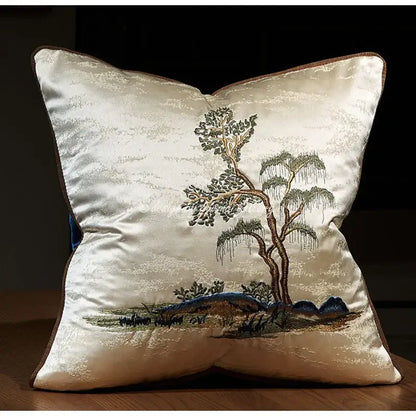 Cream-colored satin pillow cover with chinoiserie landscape embroidered featuring tree and mountains in green brown and blue