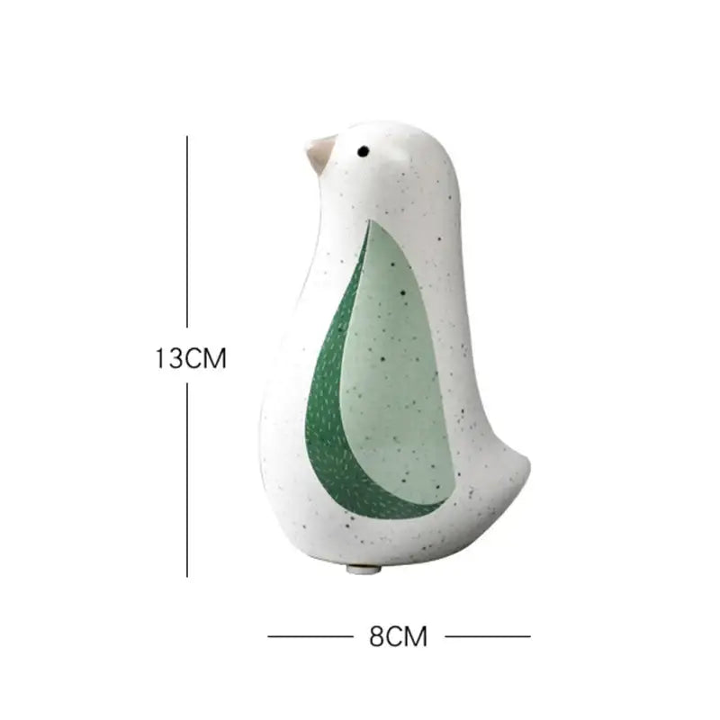 A white ceramic bird figurine with speckled texture and green leaf design from decorbites bird figurines for home decor