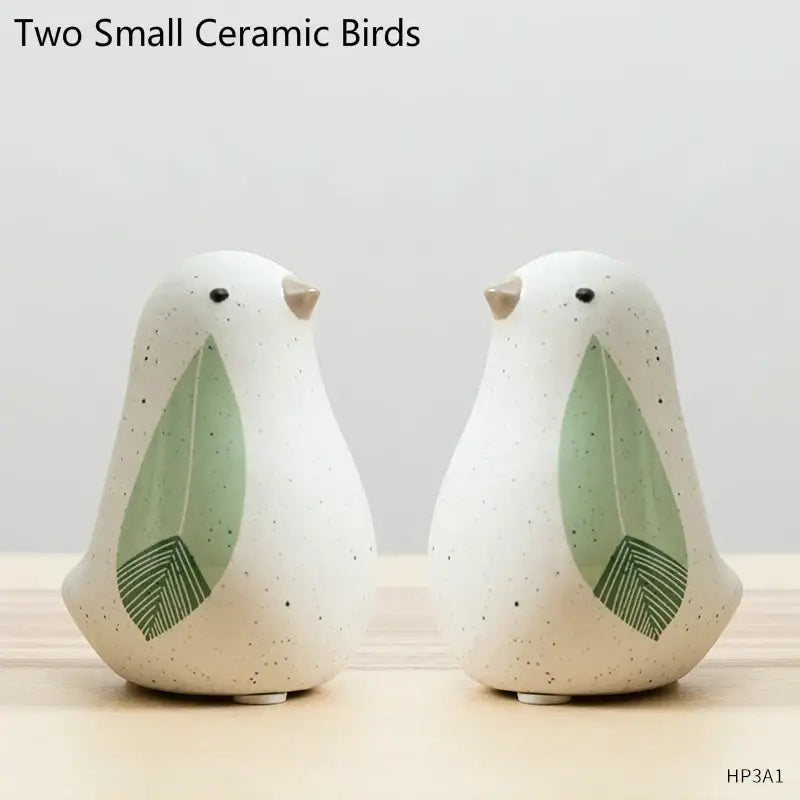 Two small speckled white ceramic bird figurines with green leaf wings and beige beaks for home decor by decorbites