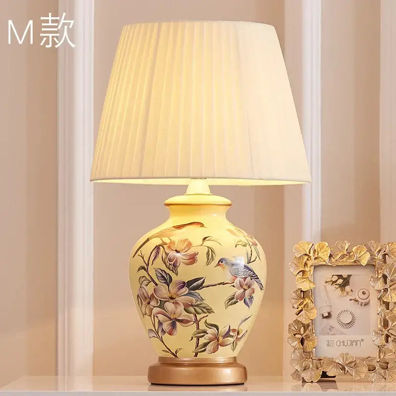 Cream-colored decorbites™ bird flower ceramic table lamp with hand-painted design and pleated off-white shade for bedroom
