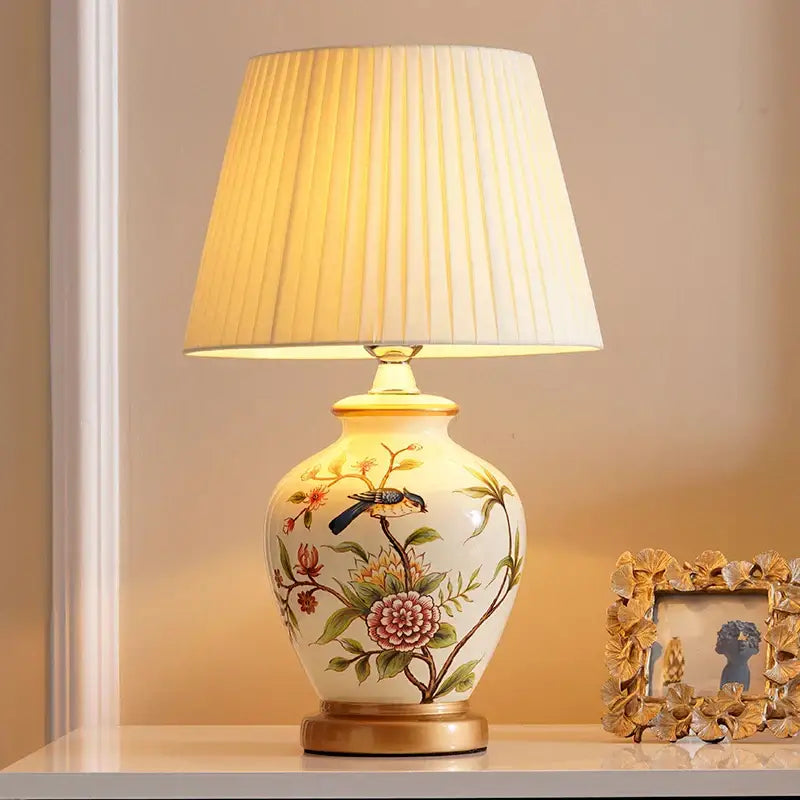 Cream-colored DecorBites™ bird flower ceramic table lamp with hand-painted design and gold-trimmed base for bedroom use