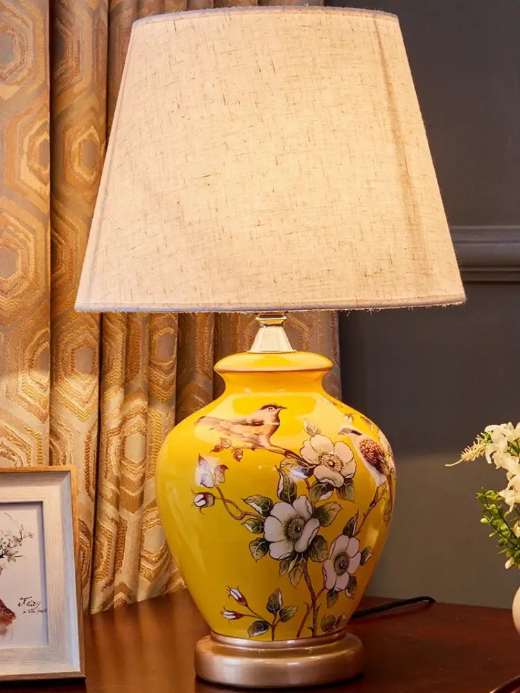 Yellow DecorBites™ bird flower ceramic table lamp with hand-painted floral design and beige linen shade for bedside use