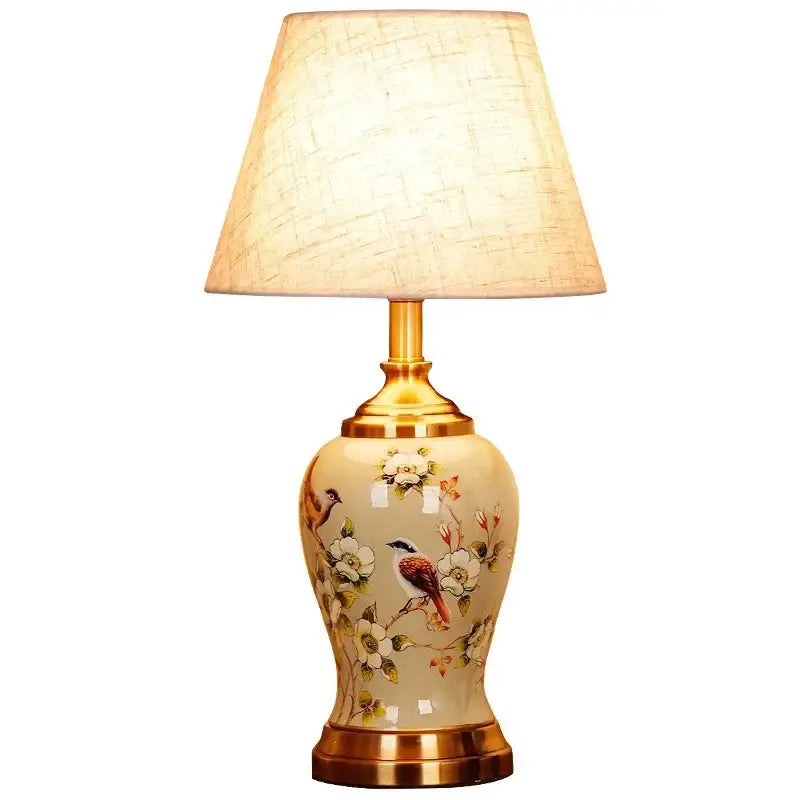 DecorBites™ ceramic table lamp in cream with gold accents and hand-painted floral and bird motifs under beige shade