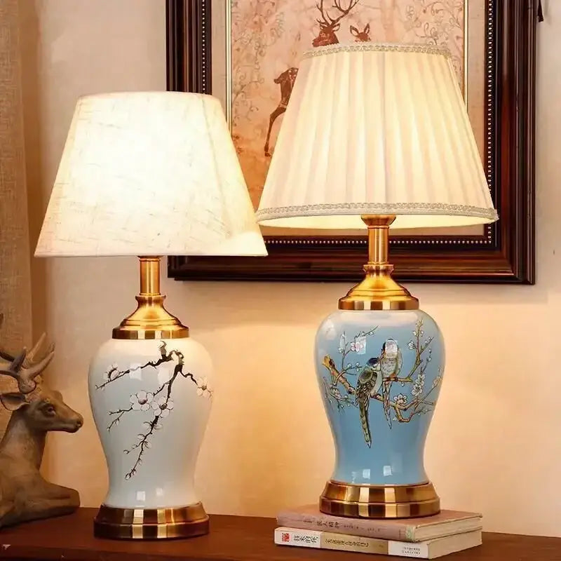 Two ceramic table lamps by DecorBites with gold metal bases glaze white with black blossoms and blue with painted birds