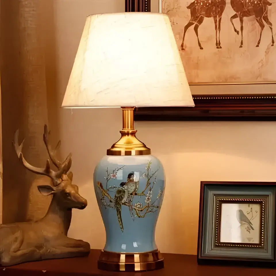 DecorBites™ ceramic table lamp in light blue with gold accents and painted bird design for living room use