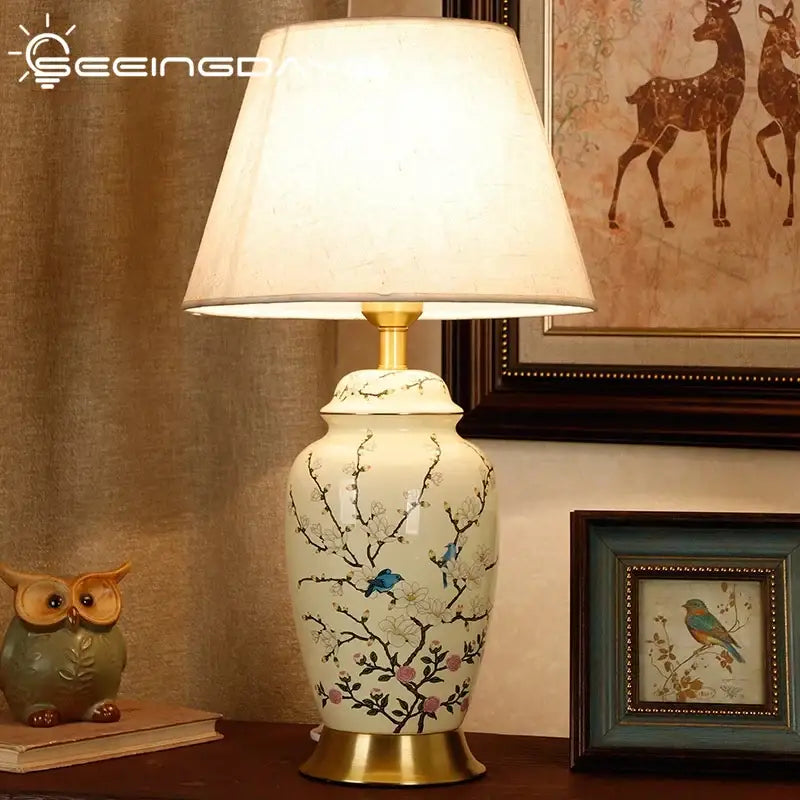 Cream-colored ceramic table lamp with hand-painted cherry blossom and blue bird motifs by DecorBites for living spaces
