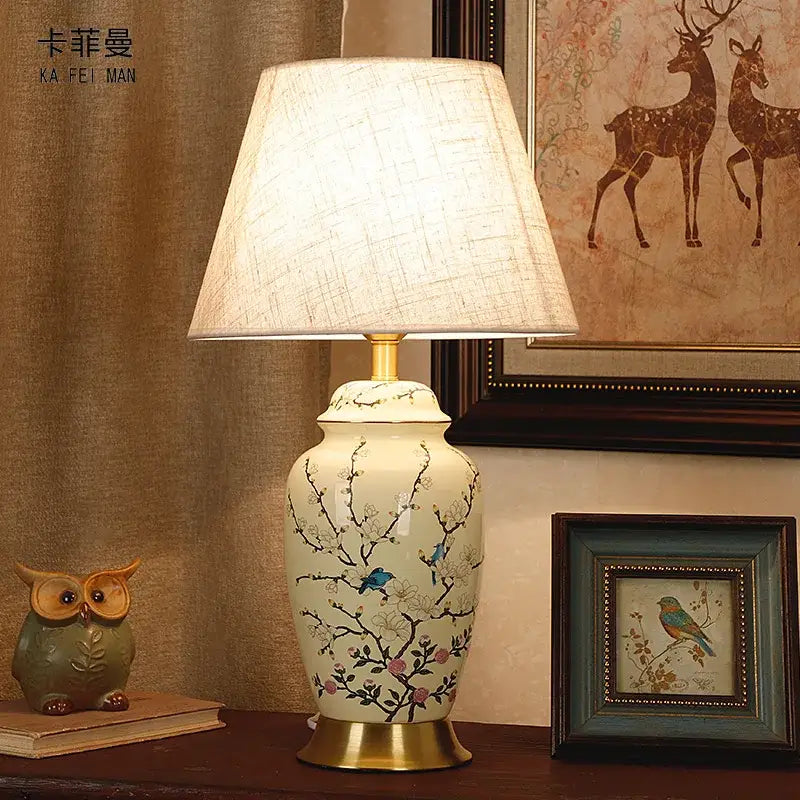 Cream-colored ceramic table lamp with hand-painted blue birds and pink blossoms by DecorBites for living room use