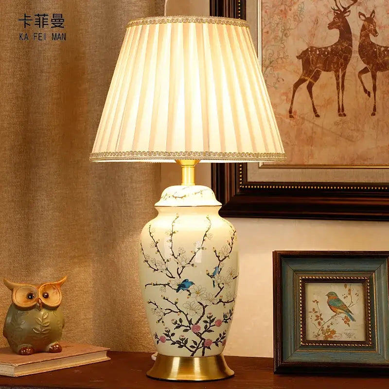 Cream-colored ceramic table lamp with hand-painted blue and pink floral patterns and gold-toned metal base