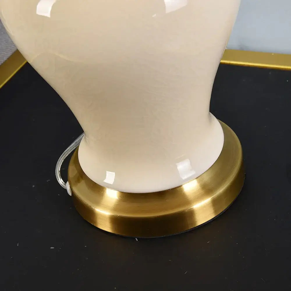Cream-colored ceramic table lamp with polished brass base for living room decor by DecorBites™