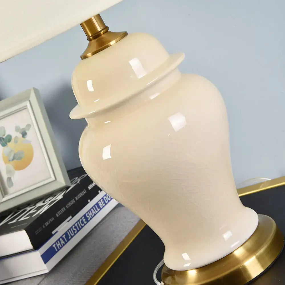 Cream-colored ceramic table lamp with glossy finish and gold metal base for living room bedside decor by DecorBites