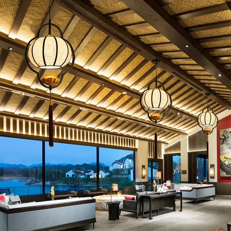 Black-framed lantern-style pendant light with beige woven fabric shades and gold accents for elegant tea house decor