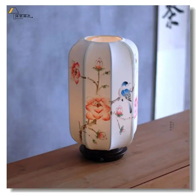 A softly glowing white ceramic desk lamp with delicate hand-painted floral and bird motifs from decorbites chinese fabric desk collection