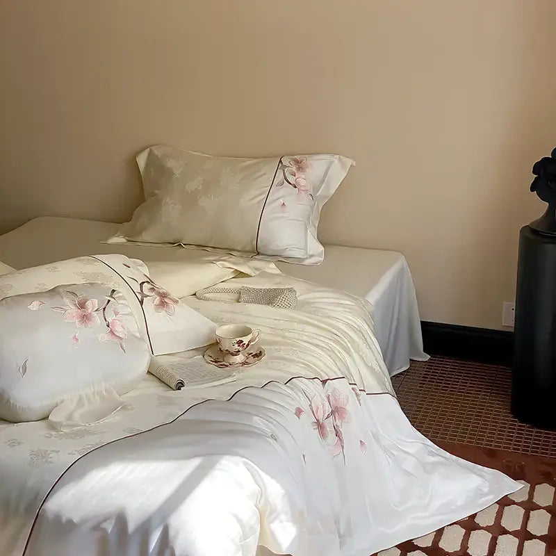 Elegant ivory satin bedding set with pink cherry blossom embroidery and black piping made of lyocell cotton by DecorBites Chinese floral