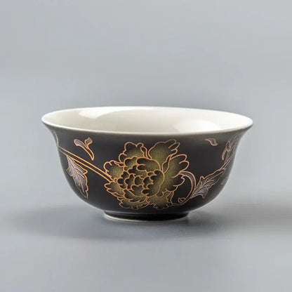 Black ceramic dragon tea cup with gold and green floral design and white interior from DecorBites porcelain set