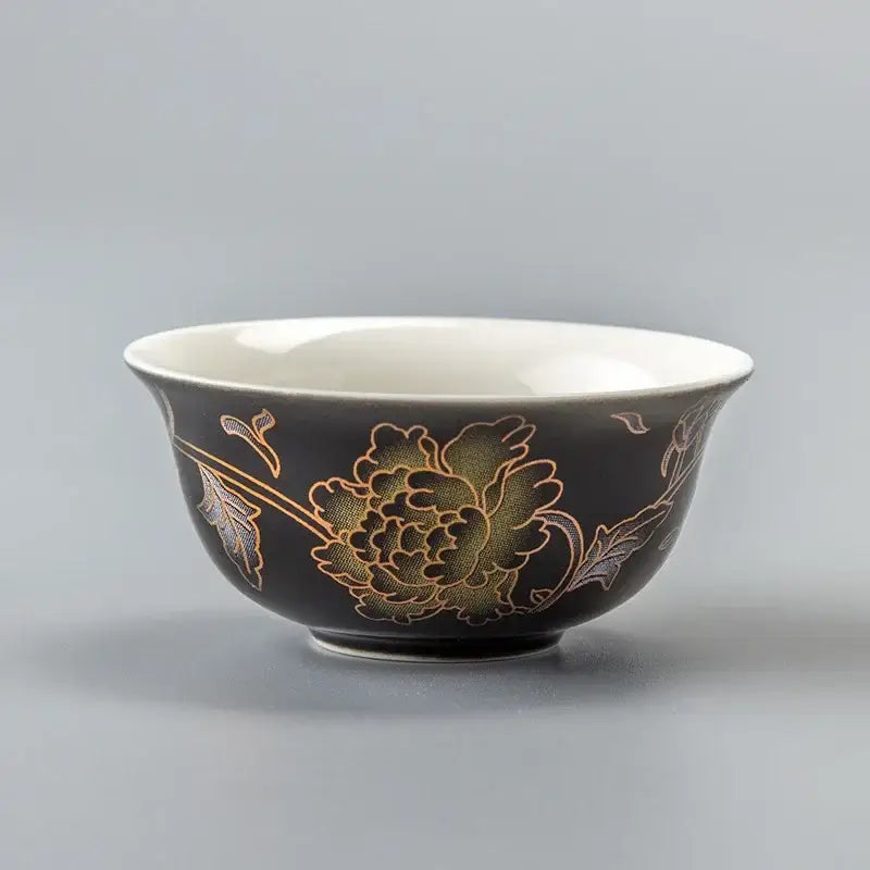 Black ceramic dragon tea cup with gold and green floral design and white interior from DecorBites porcelain set