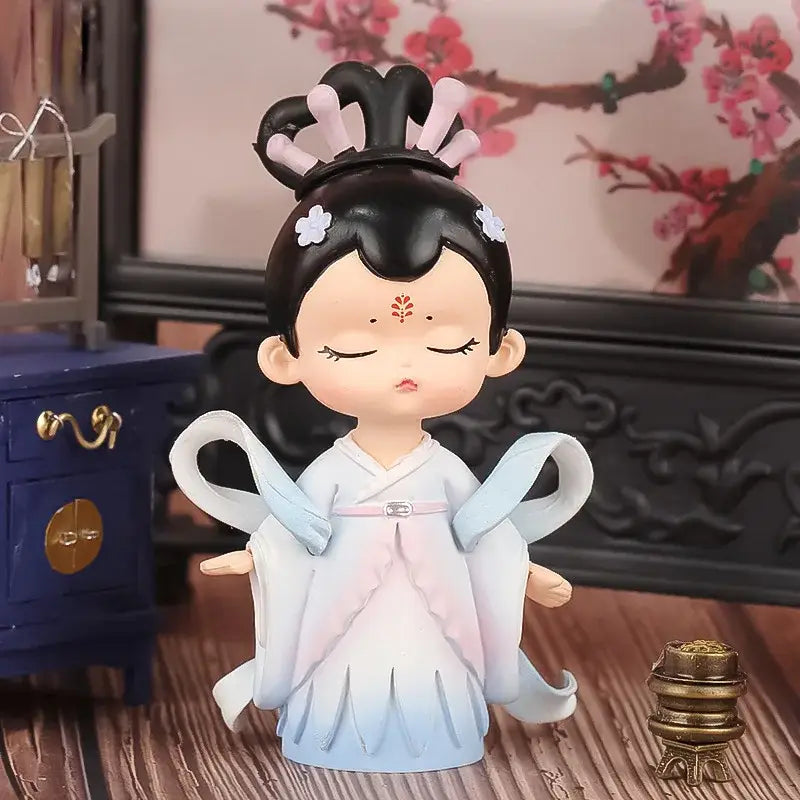 A delicate porcelain hanfu court princess figurine in light blue and pink robes with ornate headdress for bookshelf decor
