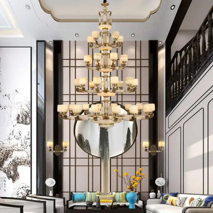 A multi-tiered decorbites jade chandelier with gold-toned metalwork and cream glass shades for modern living spaces