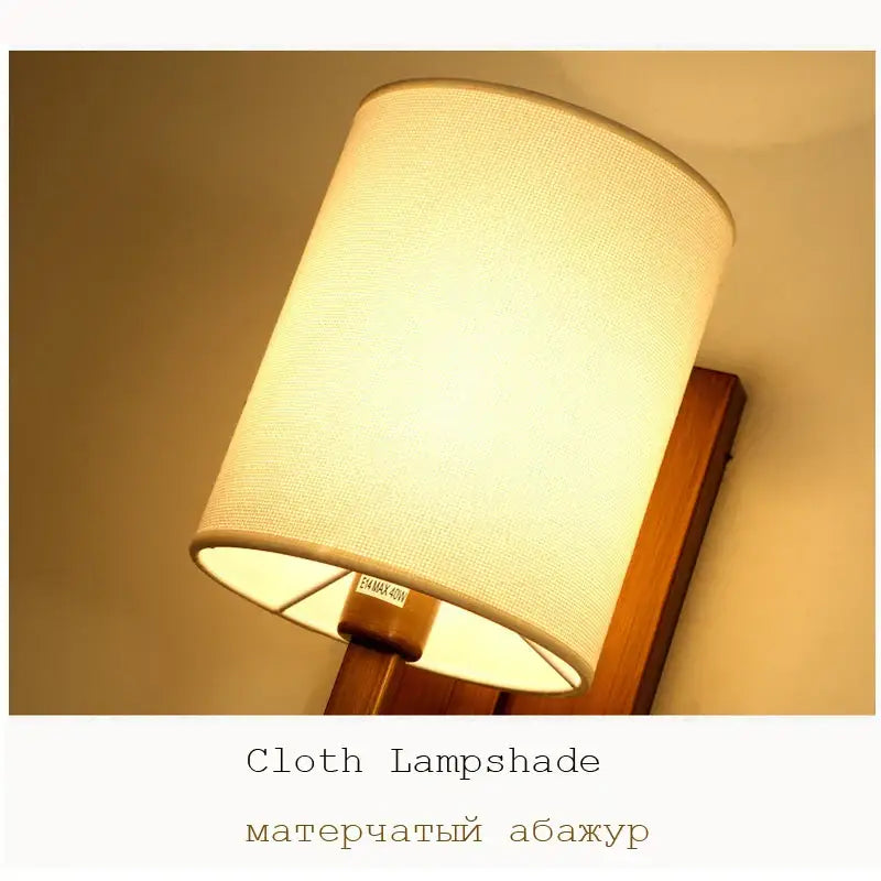 Cream-colored cylindrical lantern cloth wall light with subtle woven texture and wooden mounting bracket for decorbites bedroom use