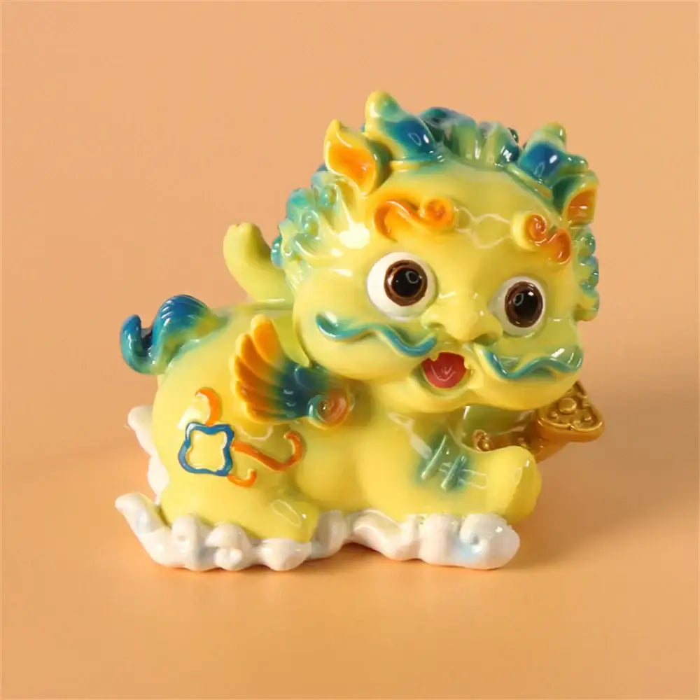 A vibrant yellow ceramic mythology lion figurine with blue and orange accents holding gold coins for luck and wealth