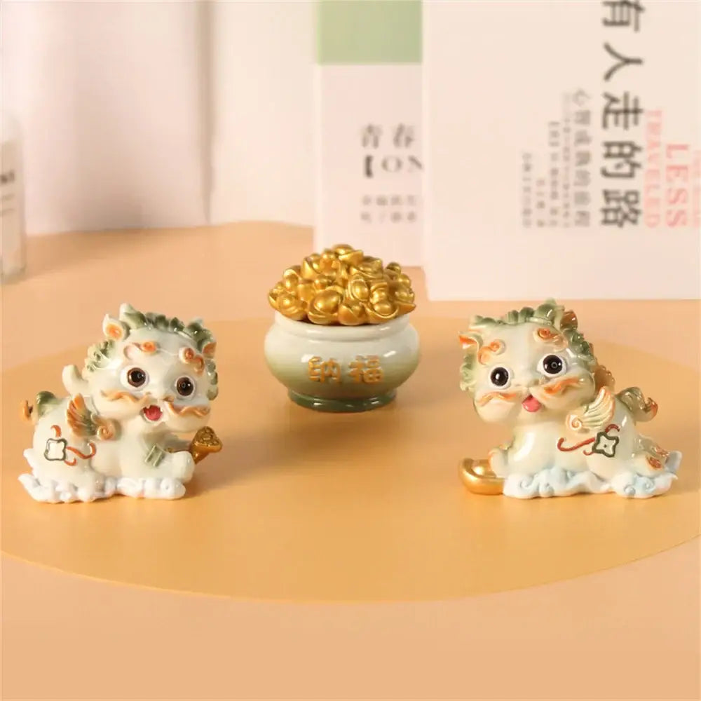 Two white and green porcelain DecorBites™ mythology lion figurines with gold accents beside a ceramic pot of coins