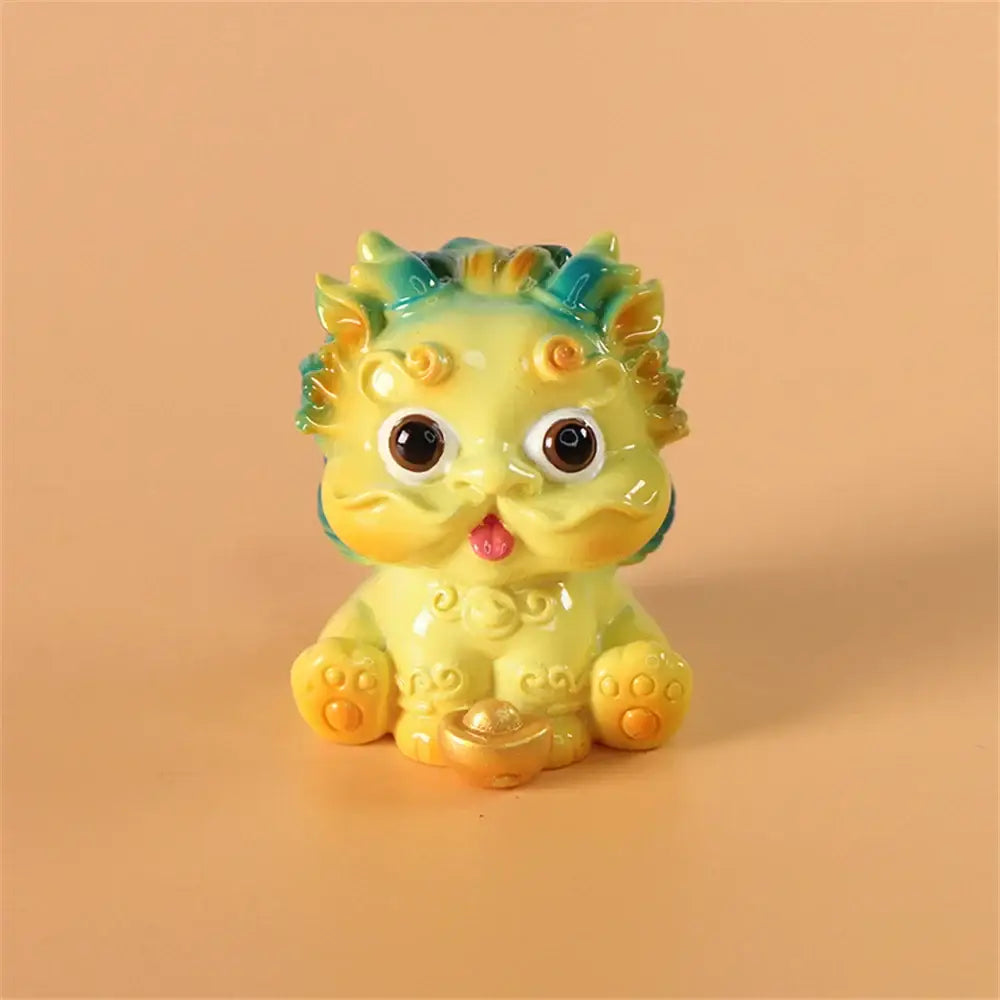 A glossy yellow ceramic mythology lion figurine with green and orange mane holding a golden ingot for luck and wealth