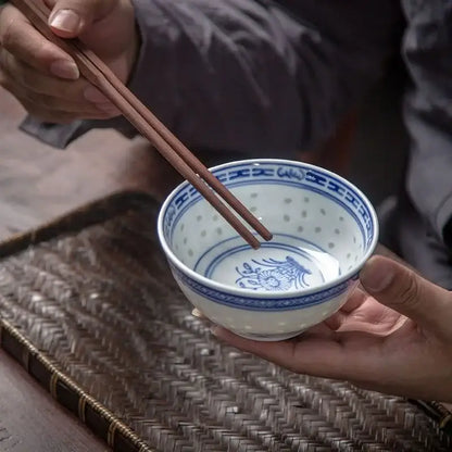 A delicate white porcelain decorbites chinese orchid dragon bowl with intricate blue floral patterns and perforated interior
