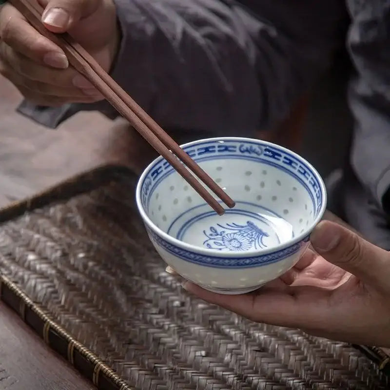 A delicate white porcelain decorbites chinese orchid dragon bowl with intricate blue floral patterns and perforated interior