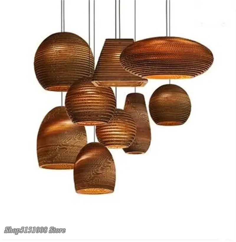 A collection of warm-toned ribbed paper and cardboard decorbites pendant lights in organic shapes hanging from cords