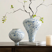 DecorBites™ Chinese retro ceramic vase in white with blue speckles and flared neck holds delicate green branches