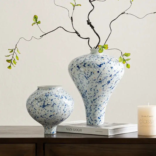 DecorBites™ Chinese retro ceramic vase in white with blue speckles and flared neck holds delicate green branches