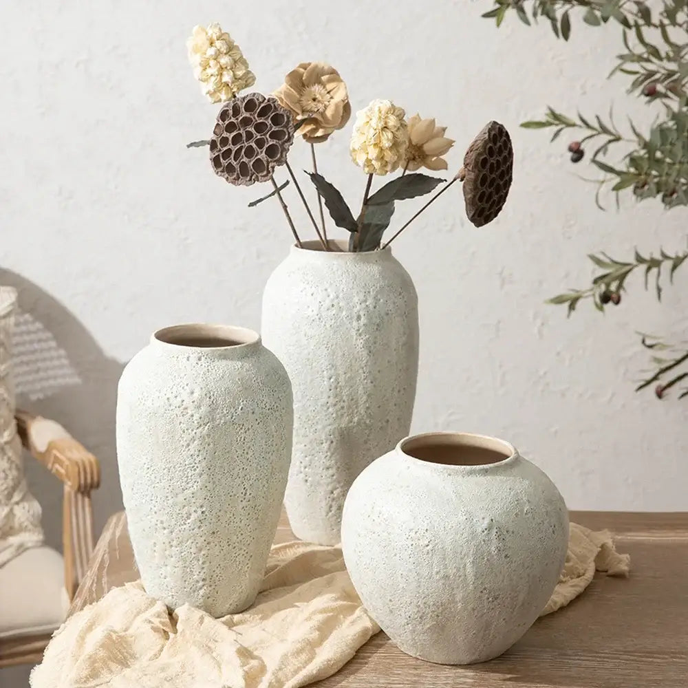 Three textured white ceramic vases in chinese style with one holding dried flowers for home decor by DecorBites™