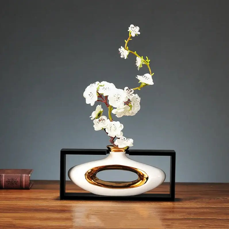 White ceramic vase with gold oval accent holding delicate white blossoms in decorbites chinese style ceramic design