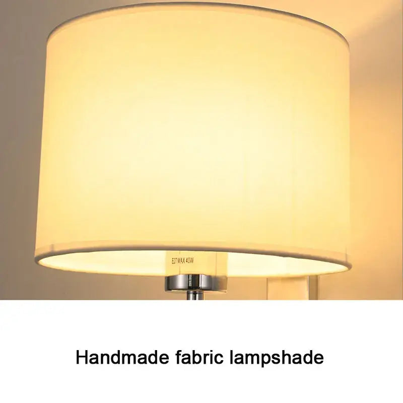 Cream-colored cloth covered wall lamp with cylindrical fabric shade and metallic base for bedroom and living room decor