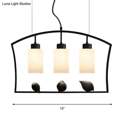 Black metal cylinder island light fixture with three frosted white glass shades and decorative bird figurines ceiling lamp