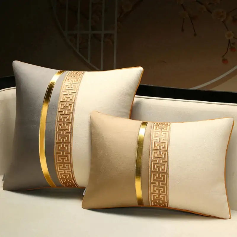 Two rectangular decorbites™ decorative pillow covers in gray and beige with gold geometric embroidery for home use