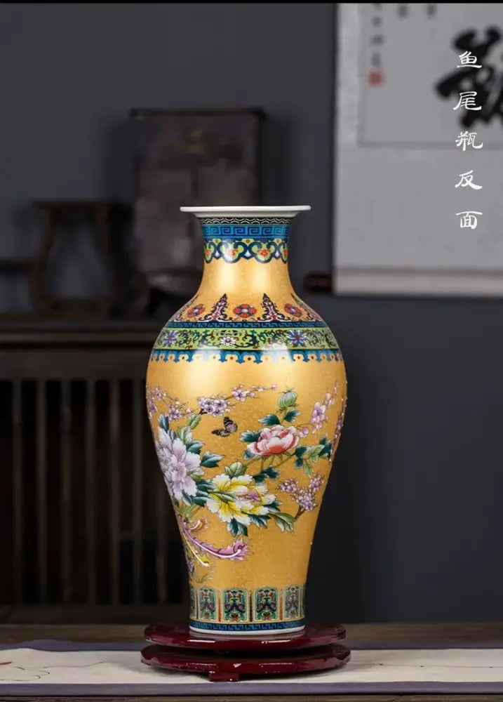 A vibrant yellow enamel colored vase with intricate floral and butterfly motifs and decorative blue and green borders