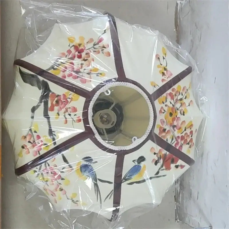 Cream-colored decorbites chinese style flower pendant light with cherry blossoms and blue birds on dark brown frame wrapped in plastic