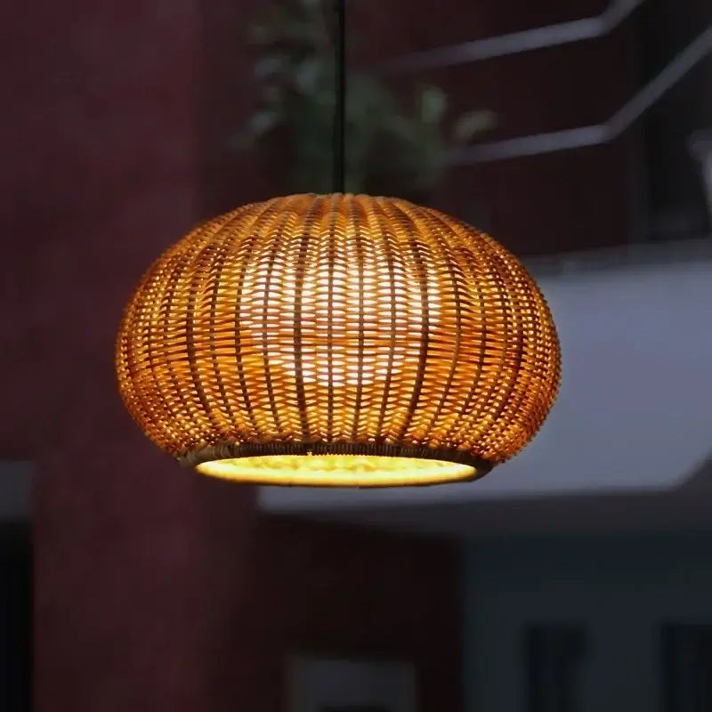 Warm-toned woven bamboo pendant light with glowing amber interior for outdoor rattan weaving pendant decor