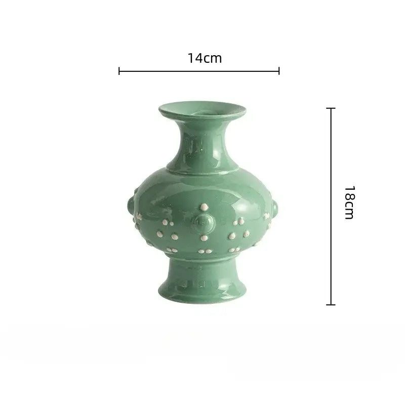 A glossy sage green ceramic vase with rounded body flared neck and white dot accents in a retro ceramic style for home decor