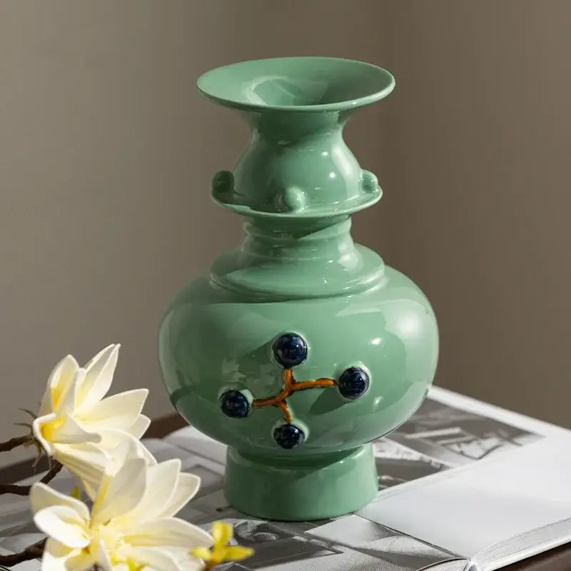 Glossy mint-green ceramic vase with bulbous body and dark blue spherical accents in a retro ceramic design for home decor