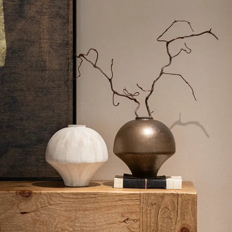 Bronze metallic retro porcelain vase with rounded body and narrow neck holding dark twisted branches for home decoration