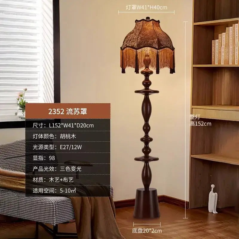 A tall dark walnut-finished decorbites chinese tassels floor lamp with an ornate fabric shade and dangling fringe