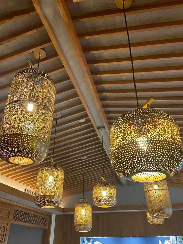 Golden intricately perforated zen art birdcage pendant light hanging from ceiling for restaurant tea room decor