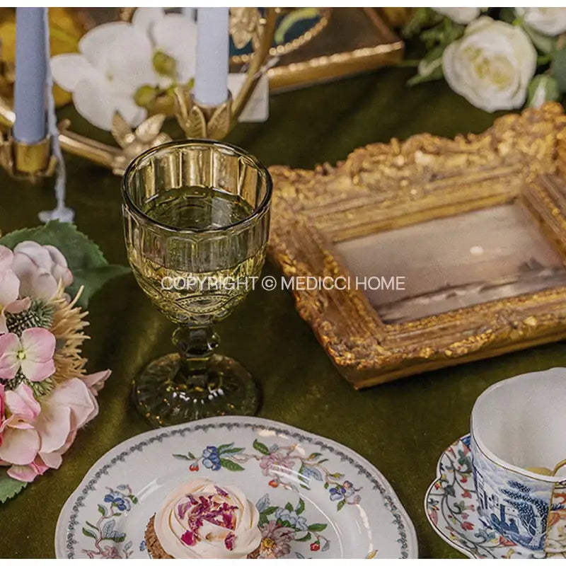 Amber-colored faceted glass wine goblet with slender stem and ornate base paired with decorbites chinoiserie floral birds dinner plate