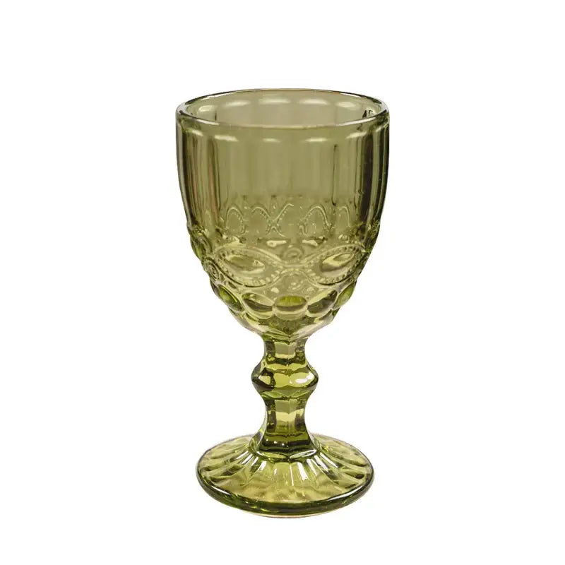 A translucent olive-green glass goblet with embossed patterns and fluted stem complementing decorbites chinoiserie floral birds dinnerware